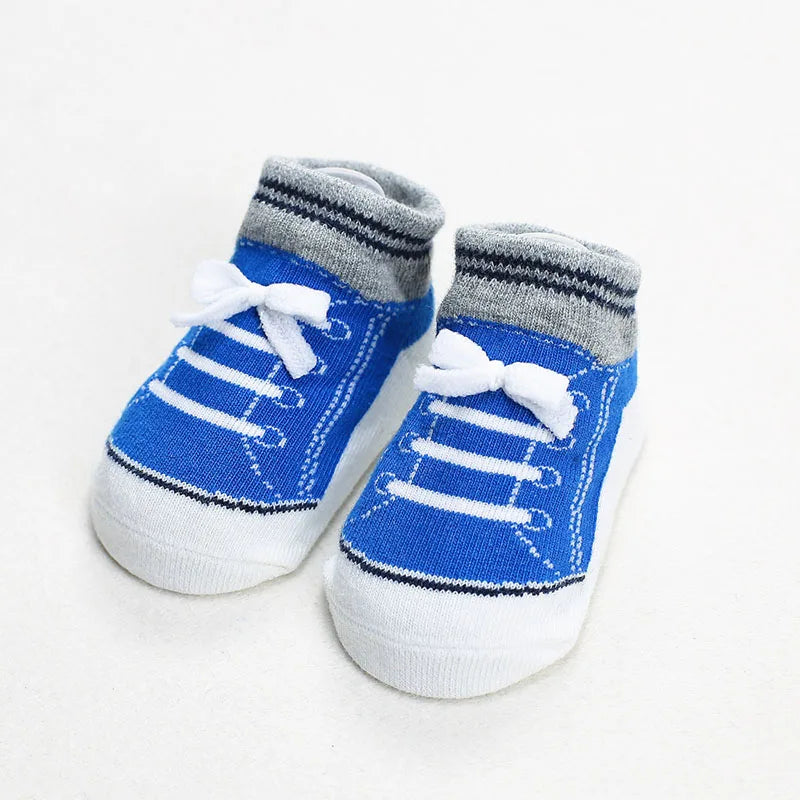 Pair of blue baby socks styled like sneakers with white bows and gray cuff trim, featuring anti-slip soles for toddlers and early walkers.